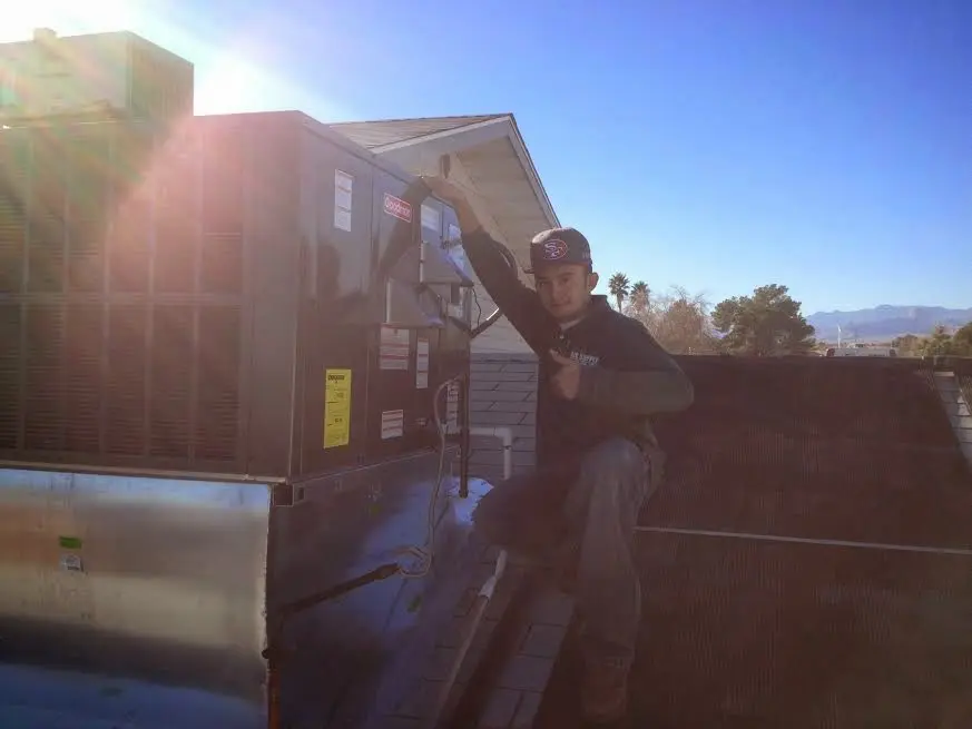 HVAC technician performing AC Tune-Up on a rooftop unit in Cuero
